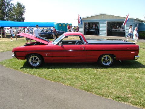 1967 Ford Ranchero - A red pickup truck with its hood open sits on display at a car show.