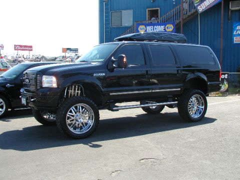 1967 Ford Ranchero - Black Ford Excursion SUV with large chrome wheels and a roof-mounted cargo box.
