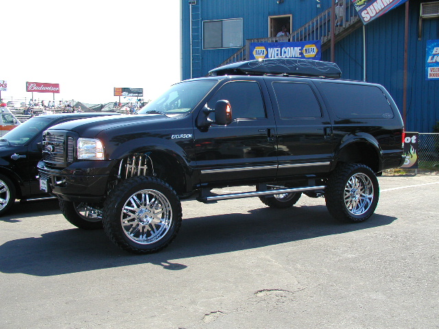 Lifted black Ford Excursion SUV with custom wheels and roof rack