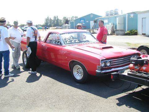 1967 Ford Ranchero - A red 1967 Ford Ranchero is parked at a drag racing event, with racing decals visible on the windshield.