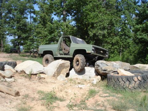 1974 Ford Bronco - This modified off-road truck navigates a rocky obstacle course with its doors removed.