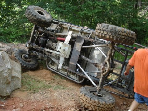 1974 Ford Bronco - An off-road vehicle has rolled onto its side during an off-road excursion, revealing its undercarriage and suspension system.