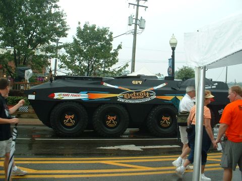 1978 Ford Mustang II - An armored vehicle with custom graphics is displayed outdoors, with several people observing.