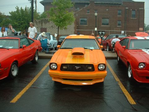1978 Ford Mustang II - Head-on front view of an orange Mustang II King Cobra-style hatchback with a hood scoop, dual hood stripes, front air dam with striping, an…