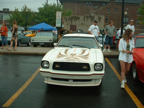 1978 Ford Mustang II - Head-on view of a white Ford Mustang II King Cobra with a large gold and brown cobra hood graphic, orange pinstriping, front air dam and qu…