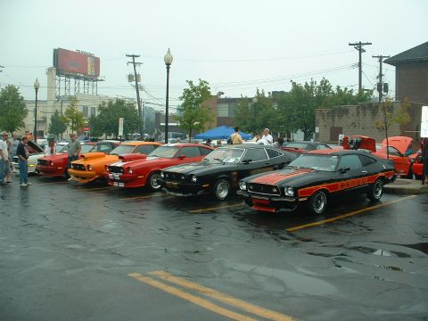 1978 Ford Mustang II - A line of classic Ford Mustang IIs are displayed at an outdoor car show on a cloudy day.