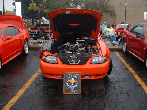 1978 Ford Mustang II - Multiple Ford Mustangs are on display at an outdoor event, with one showing its engine.