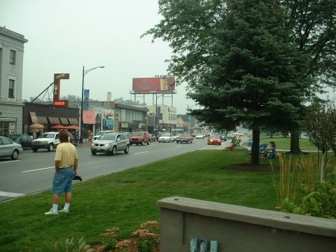 1978 Ford Mustang II - A street scene with multiple vehicles and pedestrians on a cloudy day.