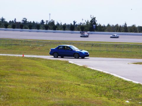 2001 Mercury Grand Marquis - A blue sedan navigates a turn on a race track with other vehicles in the background.