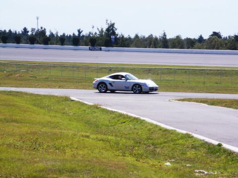 2001 Mercury Grand Marquis - A silver Porsche Cayman navigates a turn on a race track, with 'POCONO' visible on a sign in the background.