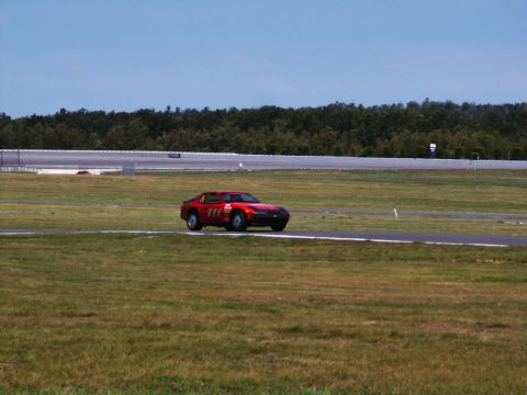 2001 Mercury Grand Marquis - A red sports car is captured in motion on a race track under a clear blue sky.