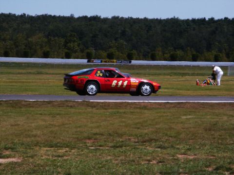 2001 Mercury Grand Marquis - A red race car with the number 611 prominently displayed on its side is seen on a race track, with a person attending to equipment in the b…