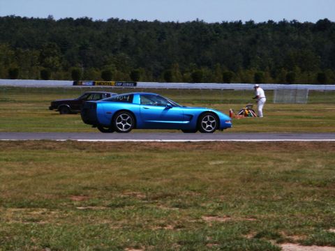 2001 Mercury Grand Marquis - A blue Chevrolet Corvette is on a race track, with another car visible in the background.