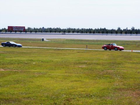 2001 Mercury Grand Marquis - Two cars race on a track, with a large advertising billboard visible in the distance.