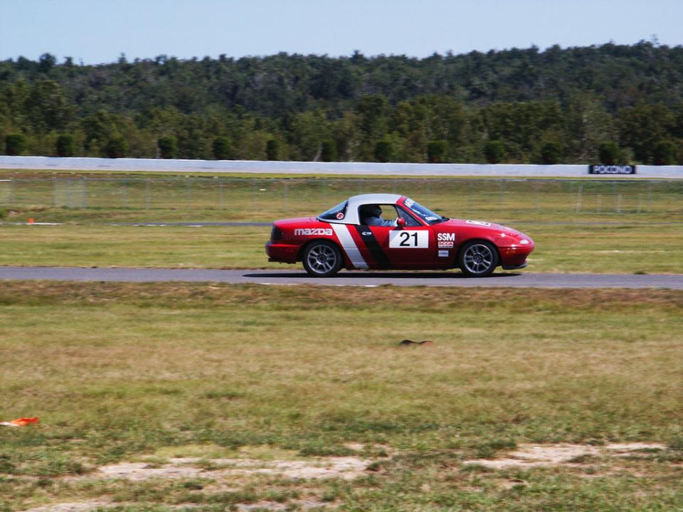 Red Mazda Miata with racing numbers 21 and SSM on a track