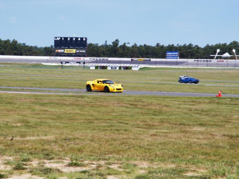 2001 Mercury Grand Marquis - Two sports cars race on a track with a scoreboard displaying lap times and track information.