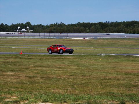 2001 Mercury Grand Marquis - A red race car numbered 611 navigates a turn on a sunny day at the Pocono Raceway.