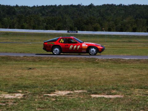2001 Mercury Grand Marquis - A red race car with sponsor decals and the number 611 is driving on a track with trees in the background.