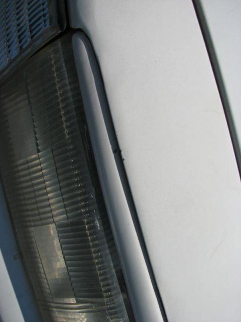 2003 Ford Crown Victoria - A detailed view of a vehicle's front corner, focusing on the headlight assembly and adjacent body panel.