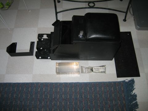 1986 Ford F-150 - A black center console is laid out with various mounting brackets and hardware for installation.