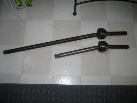 1986 Ford F-150 - Two drive shafts are laid out on a tiled surface, with a dark carpet visible at the bottom.