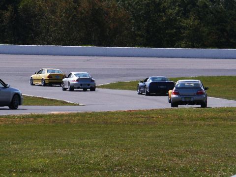 2001 Mercury Grand Marquis - Cars compete on a paved track with grassy areas and trees in the background. A watermark reads 'SUPERMOTORS.NET'.