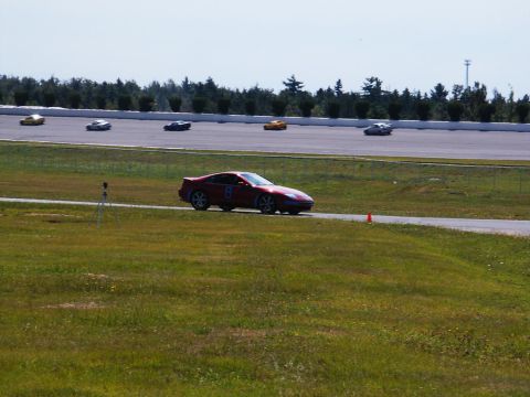 2001 Mercury Grand Marquis - Several cars race on a track under a clear sky.