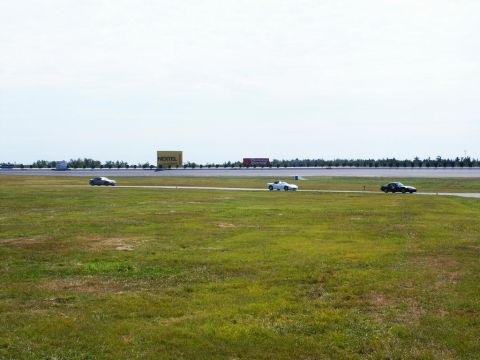 2001 Mercury Grand Marquis - Cars race on a track with a large NEXTEL billboard visible in the distance under a clear sky.