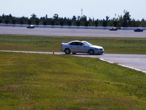 2001 Mercury Grand Marquis - A silver Cadillac CTS-V is seen on a race track with other vehicles in the background.