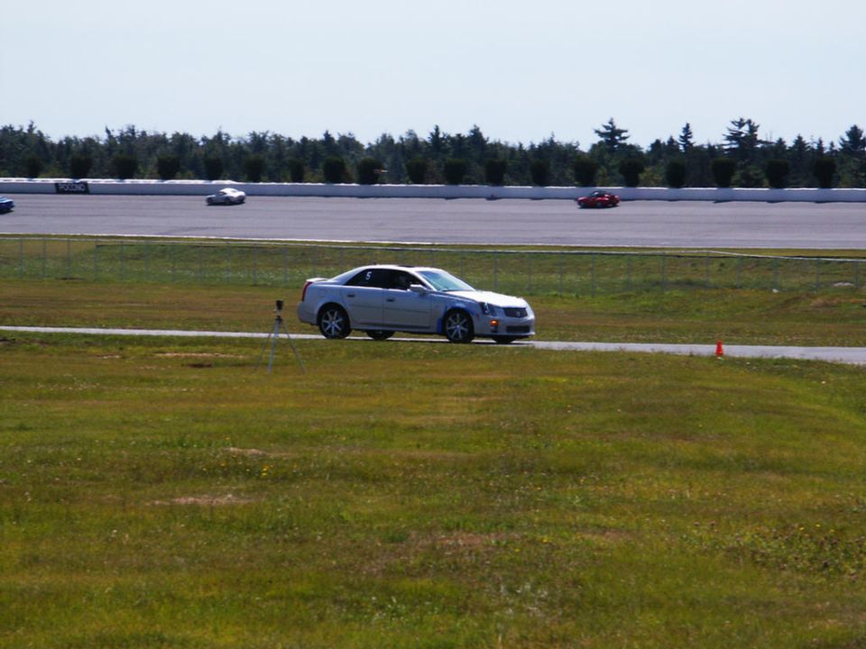 Silver sedan on a race track with other cars in the distance