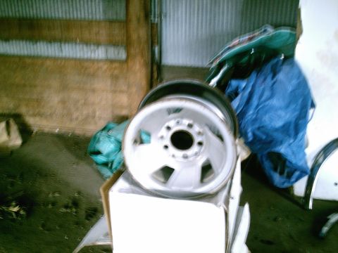 2001 Dodge 2500 - A single truck wheel is shown in a garage setting, resting on a cardboard box.