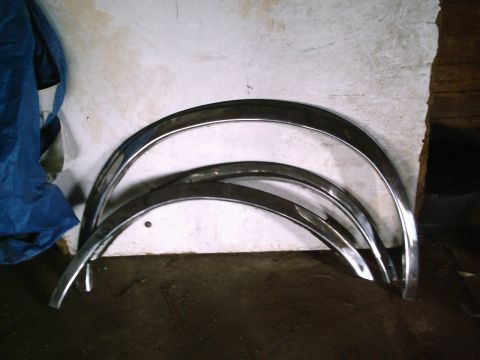 2001 Dodge 2500 - Chrome fender trim pieces are displayed against a wall, with a blue tarp to the left.