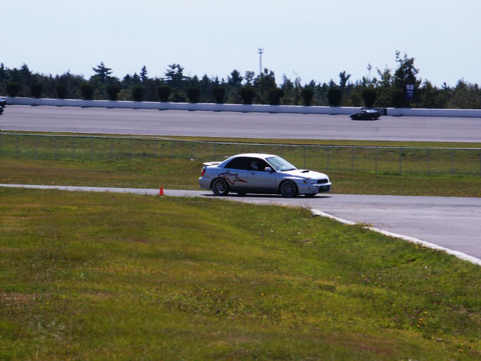 Silver Subaru WRX STI on race track with racing stripes