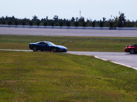 2001 Mercury Grand Marquis - A blue sports car drives on a race track, with a red car visible in the distance.