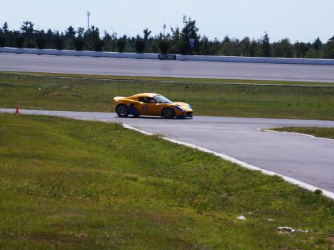 2001 Mercury Grand Marquis - A yellow sports car navigates a turn on a race track under a clear sky.