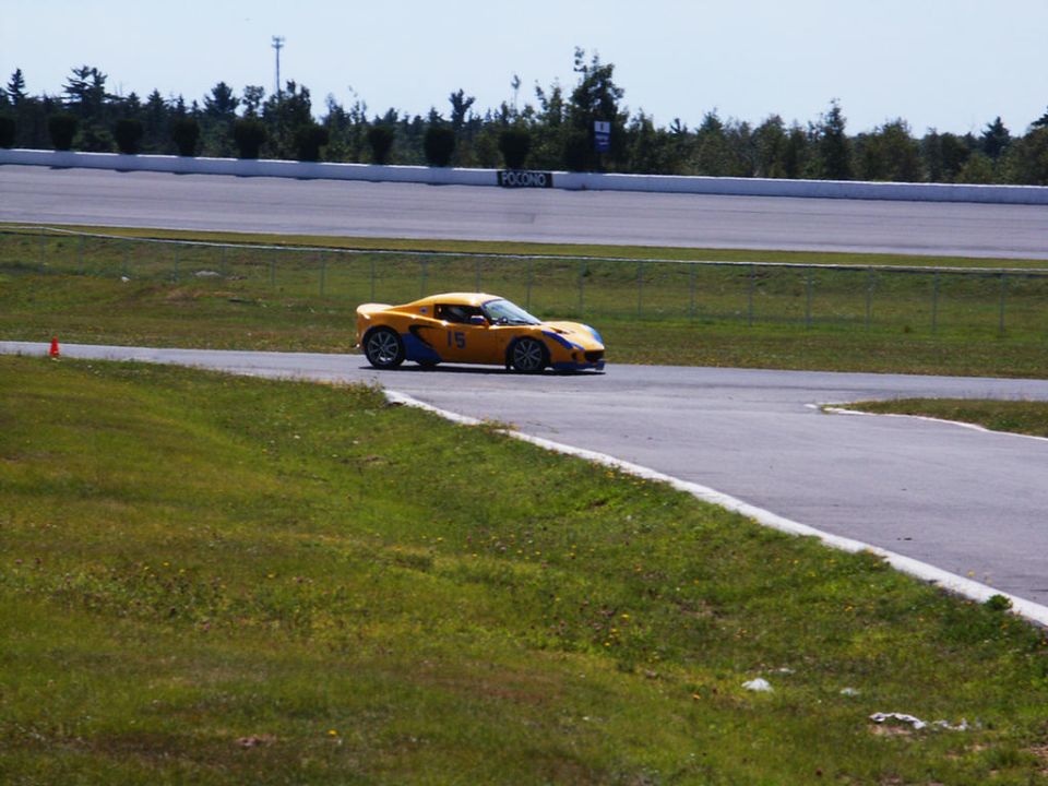 Yellow sports car with blue accents and number 15 on the side, driving on a race track