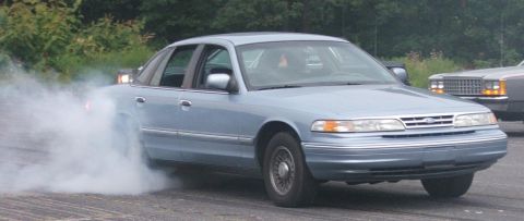 1985 Ford LTD Crown Victoria - A light blue 1992 Ford Crown Victoria performs a burnout, with another vehicle visible in the background.