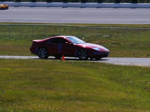 2001 Mercury Grand Marquis - A red sports car navigates a turn on a race track, with another vehicle in the distance.