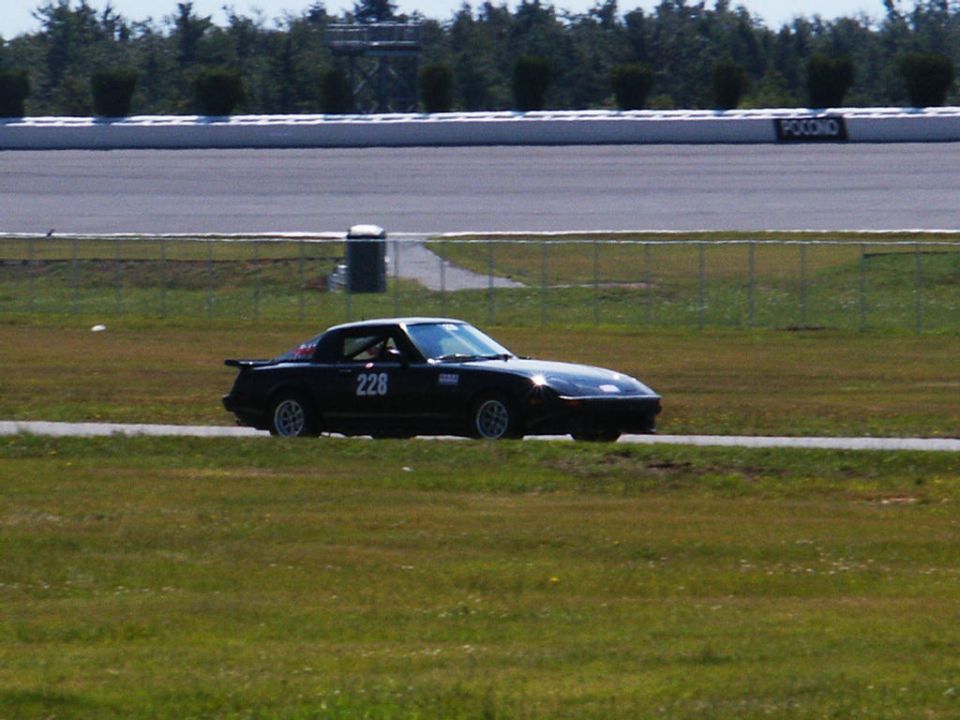 Black sports car with number 228 on the door, on a race track