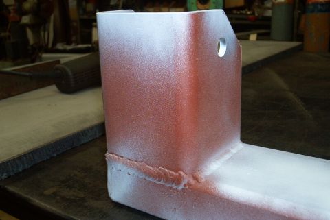 1983 Ford Bronco - A metal component, possibly a crossmember, is shown with a red base coat and white overspray, revealing visible welds.