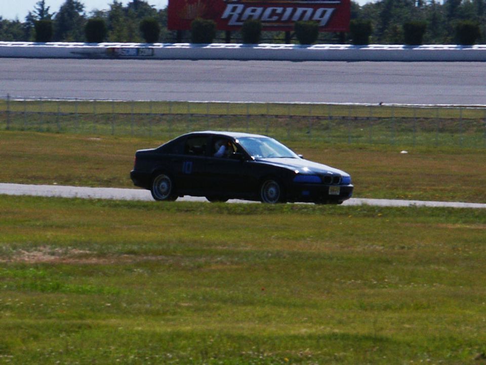 Dark sedan with racing number 10 on door, on a racetrack