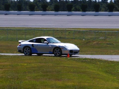 2001 Mercury Grand Marquis - A silver Porsche 911 with racing decals is on a track, with a cone nearby.