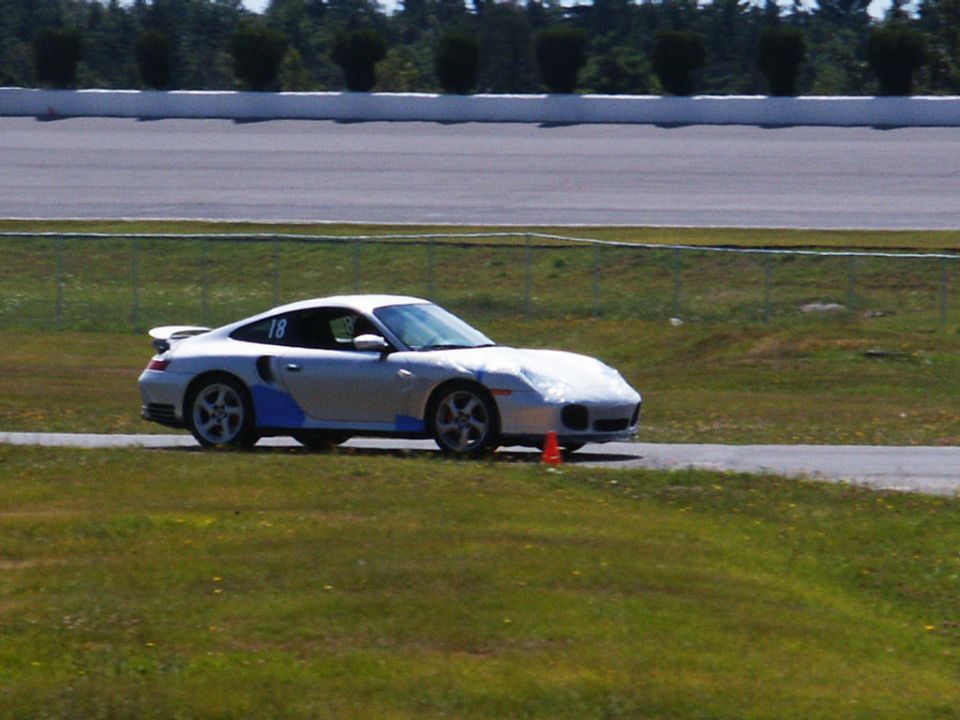 Silver Porsche 911 with blue accents and number 18 on the door, on a race track