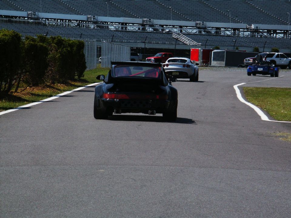 Black sports car with a rear spoiler on a race track, other cars in background