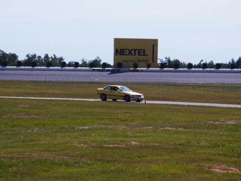 2001 Mercury Grand Marquis - Yellow BMW E36 coupe driving on a racetrack, with a large NEXTEL billboard visible.