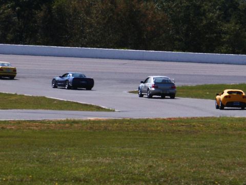2001 Mercury Grand Marquis - Multiple cars race on a track, with a yellow car, a blue sports car, a silver sedan, and another yellow sports car visible.