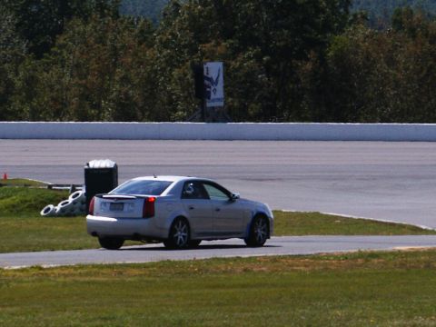 2001 Mercury Grand Marquis - A silver sedan drives on a race track, with the Supermotors.net logo visible in the lower right corner.
