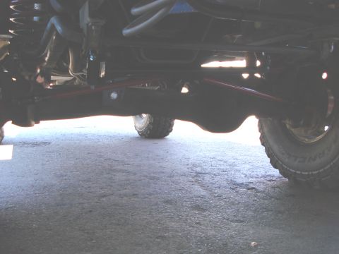 1994 Ford Bronco - Close-up view of a vehicle's undercarriage, highlighting suspension components and the rear differential. The Supermotors.net logo is prese…