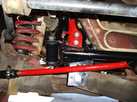 1994 Ford Bronco - Close-up view of red sway bar and red coil spring on a vehicle's undercarriage, likely part of an aftermarket suspension upgrade.