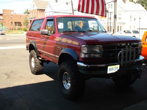 1994 Ford Bronco - This red 1994 Ford Bronco features large off-road tires and a distinctive grille guard, suggesting it's ready for adventure.